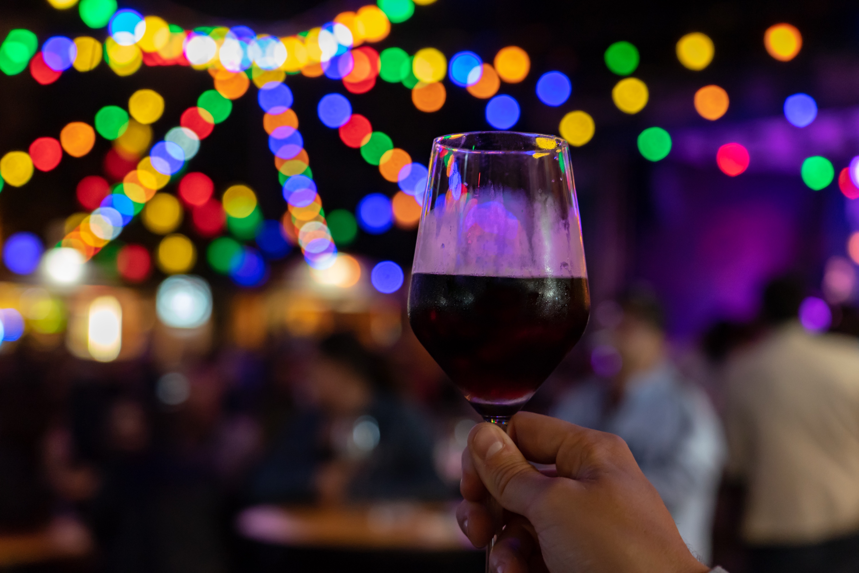 Glass of red wine with warm festival lights in the background at dusk