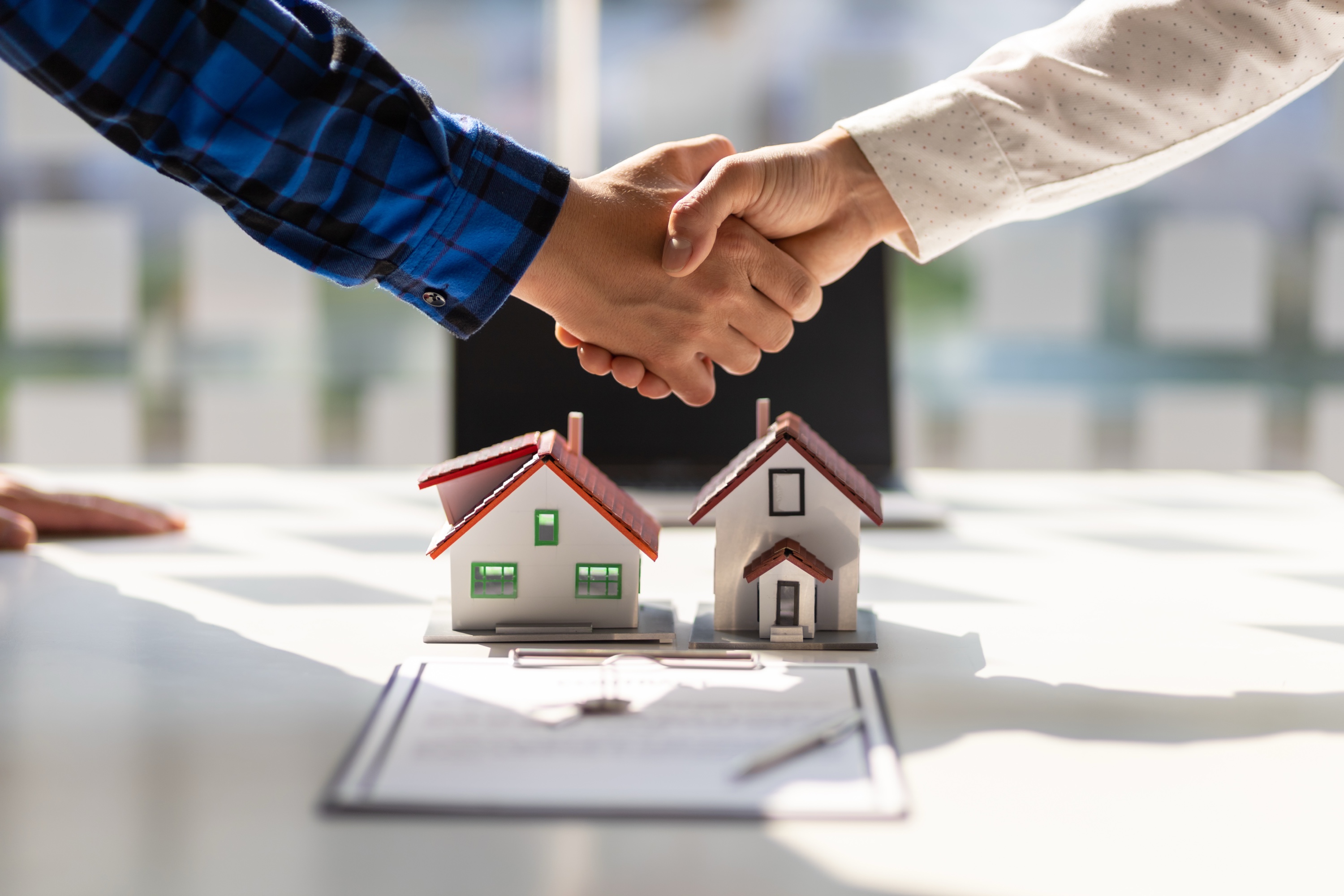 Two real estate agents shaking hands over a contract signing