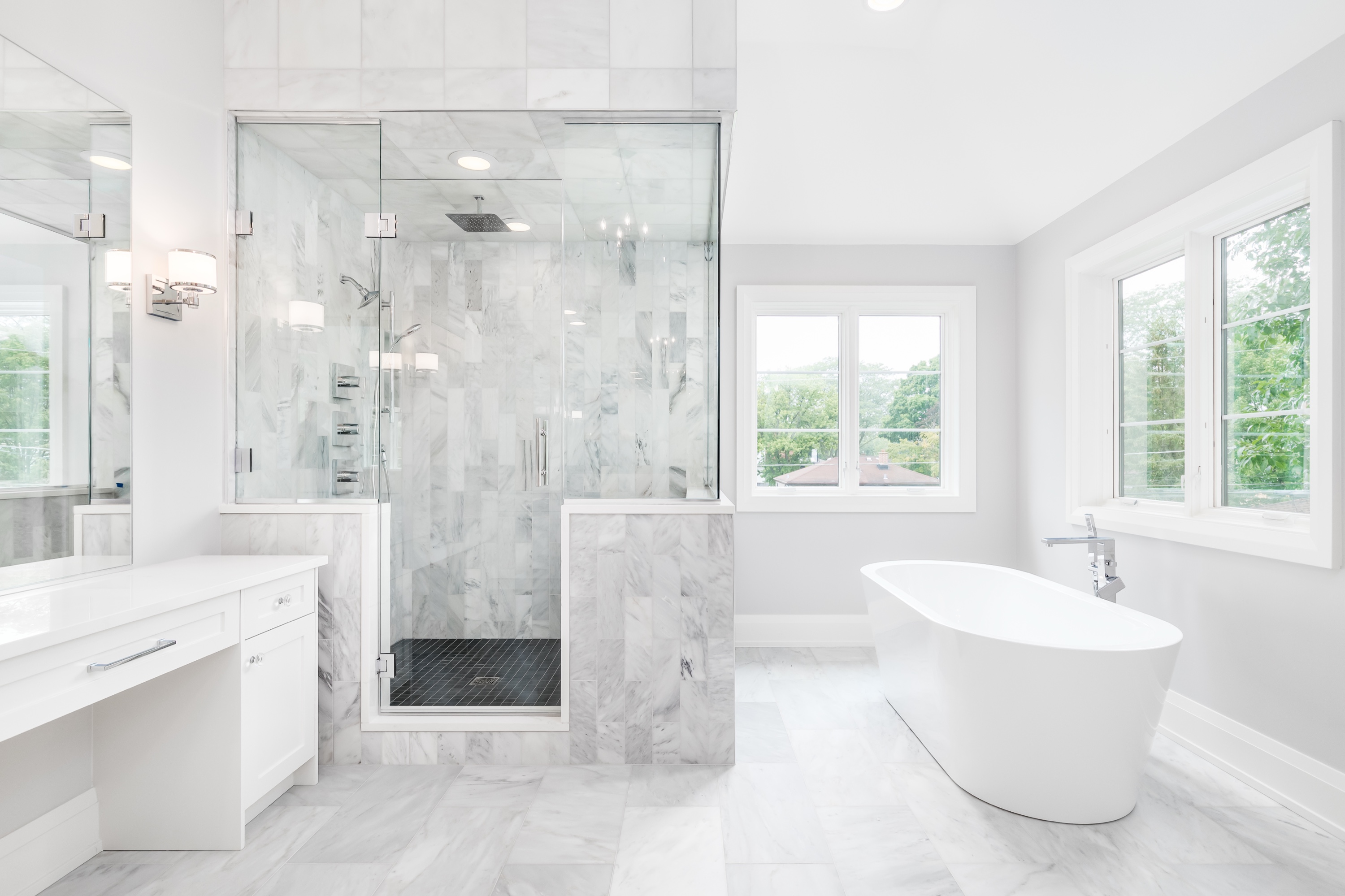 Bright luxury Silicon Valley bathroom with all-white Carrara marble, freestanding modern tub, glass-enclosed walk-in shower, and natural light