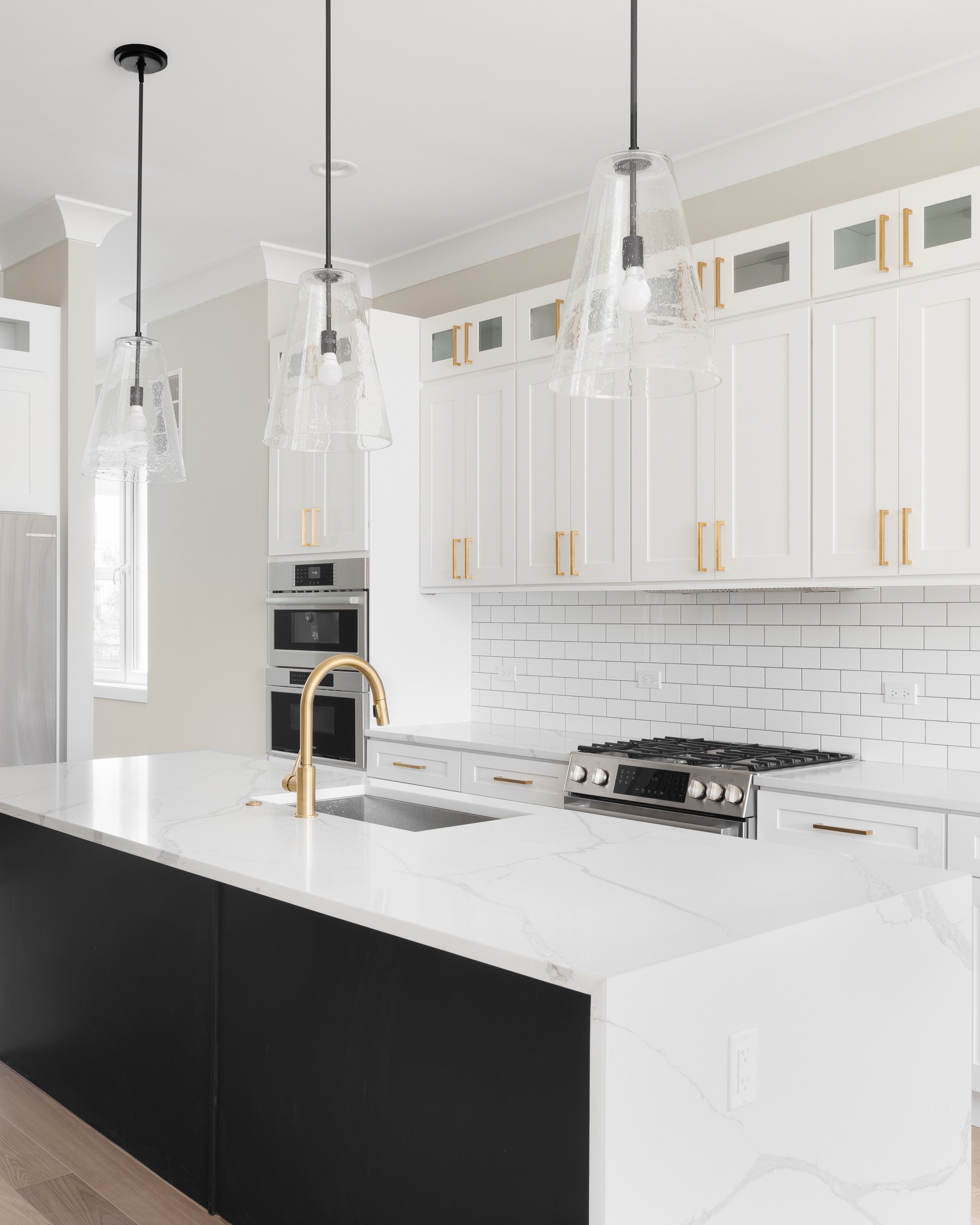 Renovated kitchen with waterfall granite island and pendant lighting