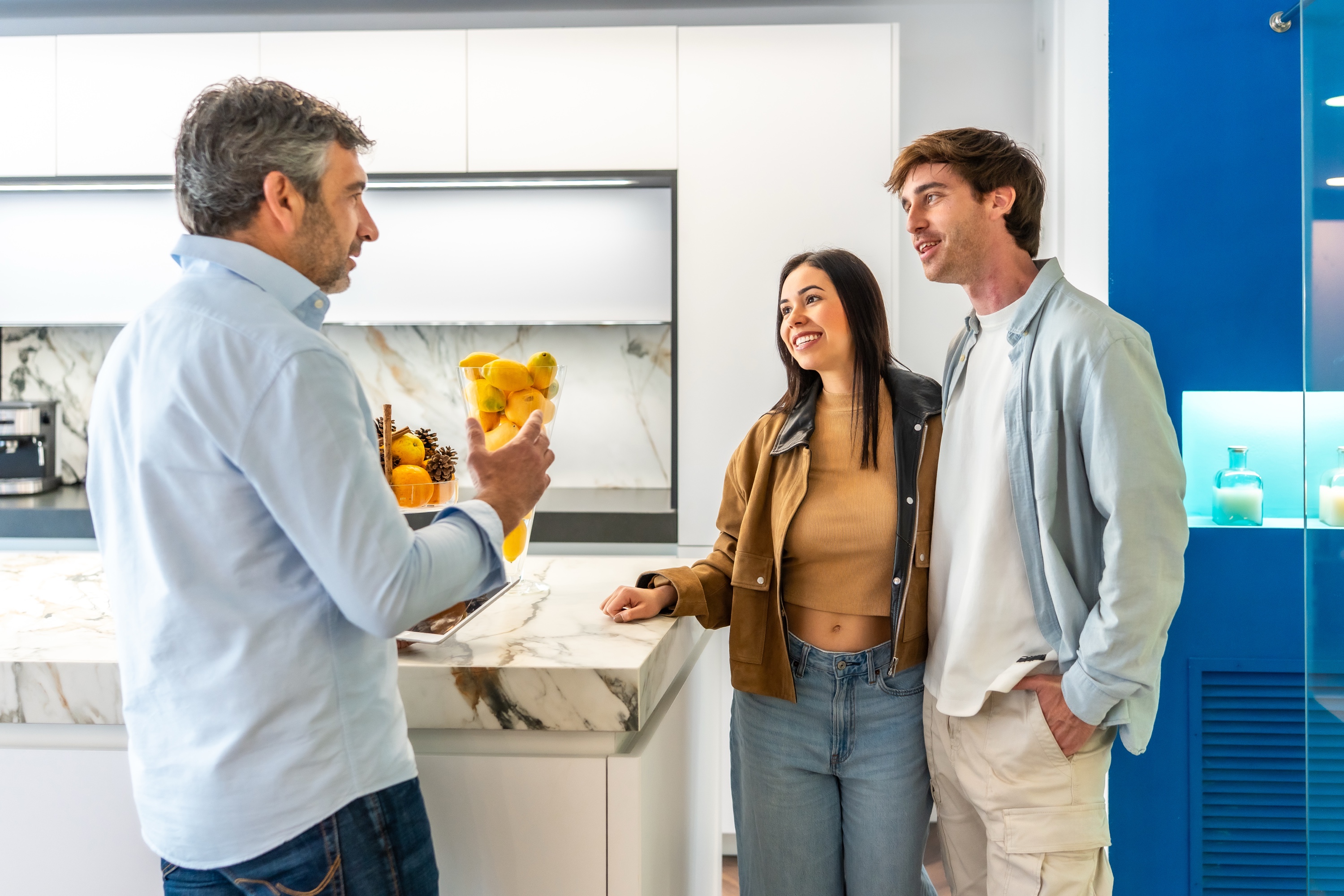 Interior designer reviewing kitchen finish samples with a young couple in a showroom