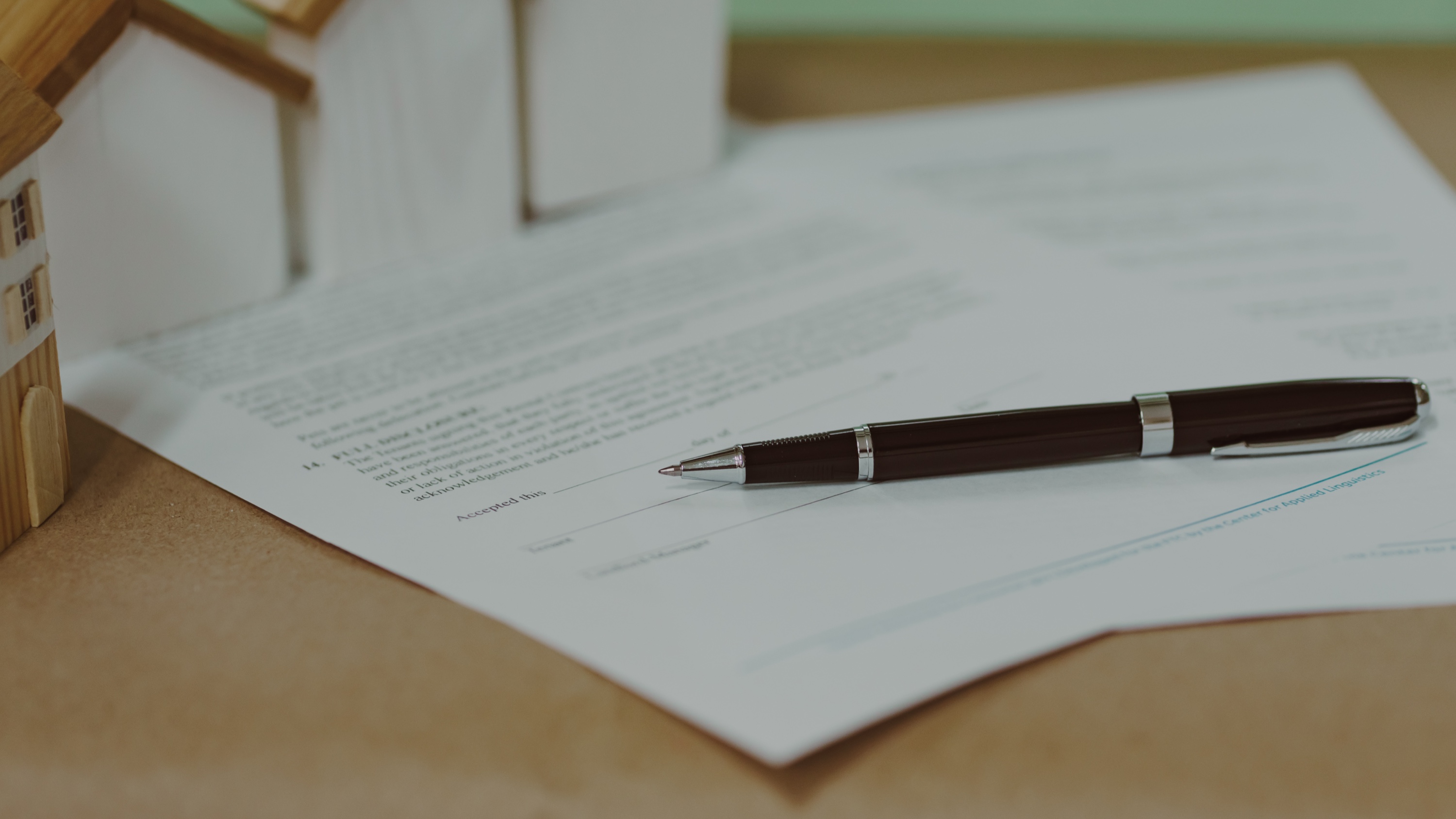 Real estate contract with miniature houses representing 1031 exchange paperwork