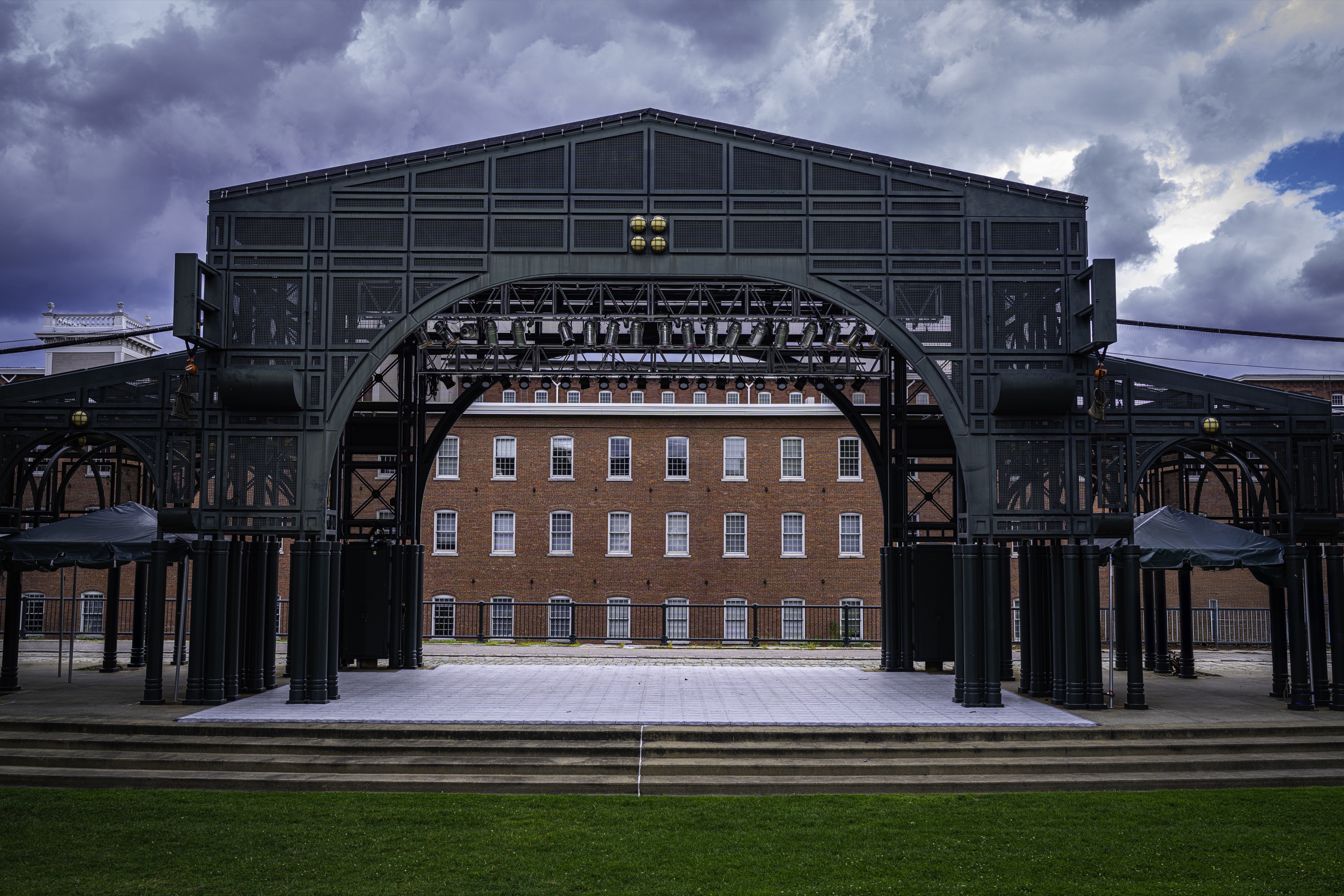 Grassy outdoor concert lawn with a stage set for an evening performance