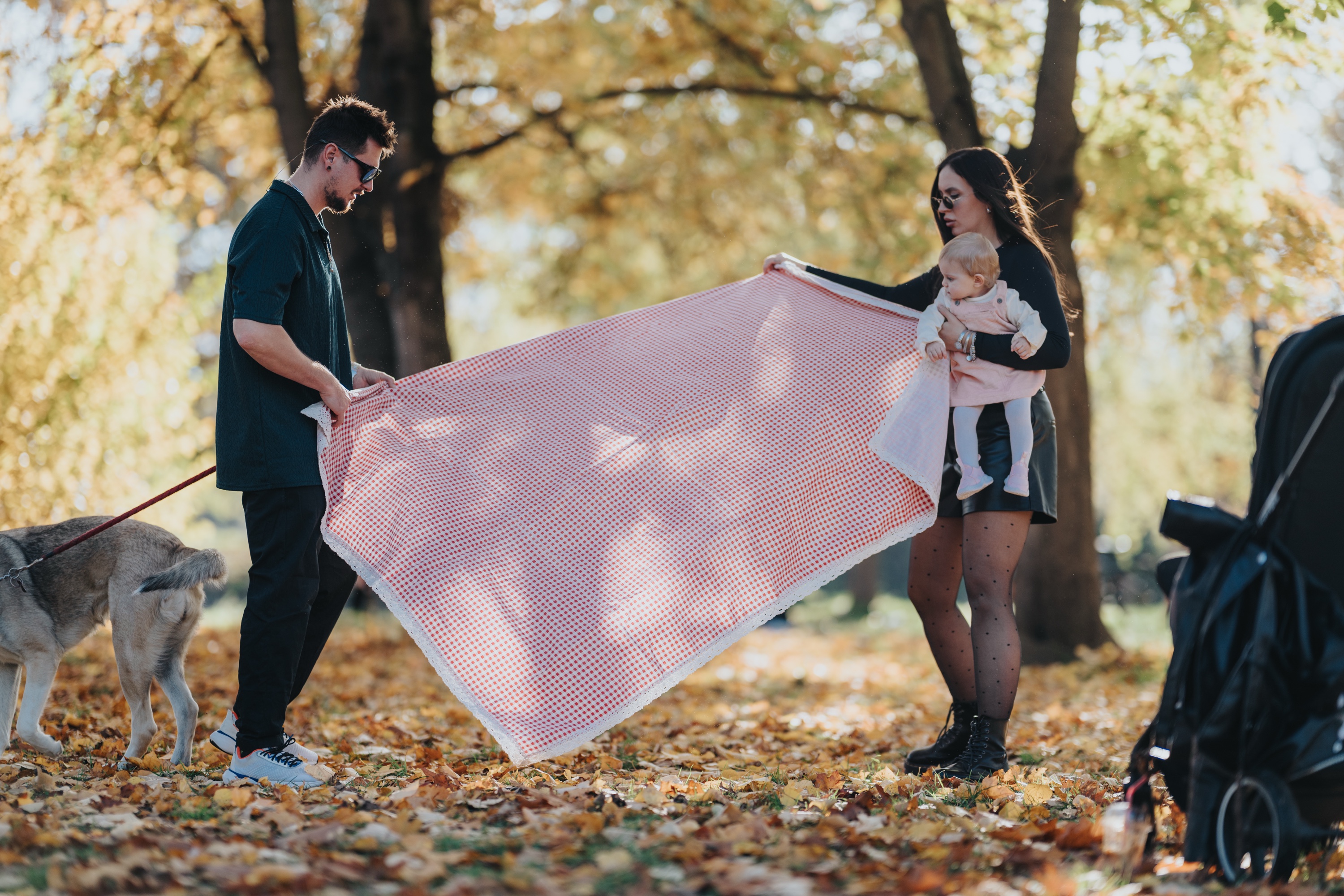 Family relaxing on a blanket in a park on an early autumn afternoon