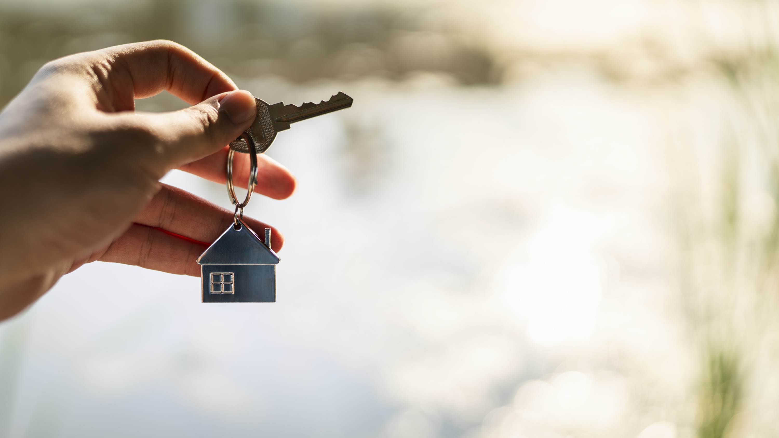 Hand holding key with house-shaped keychain